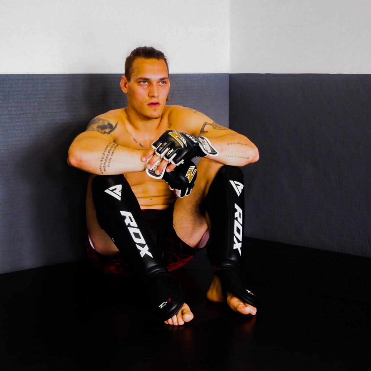 Bero Klahr sitzend in der Ringecke mit MMA-Handschuhen und Schienbeinschonern